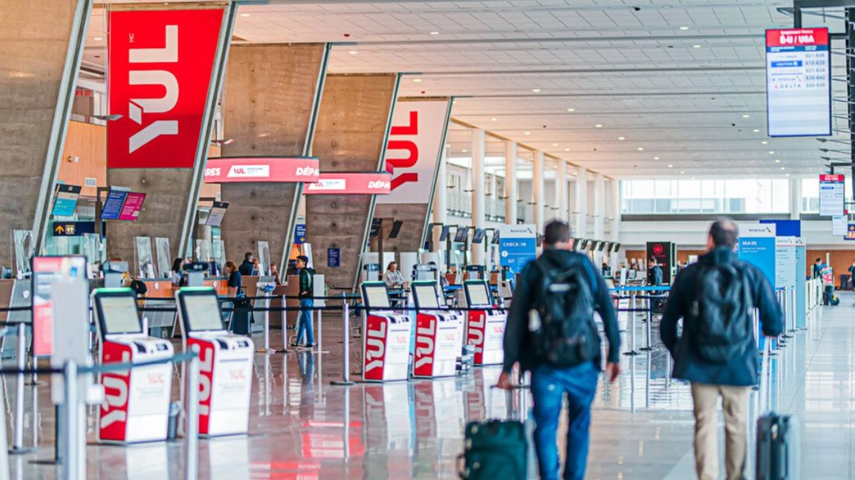 Deux personnes de dos transportent leur valise à l'aéroport de Montréal.