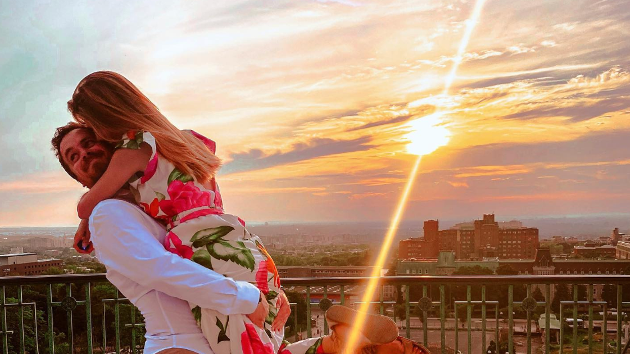 Deux personnes enlacée devant le panorama de Montréal au soleil couchant.