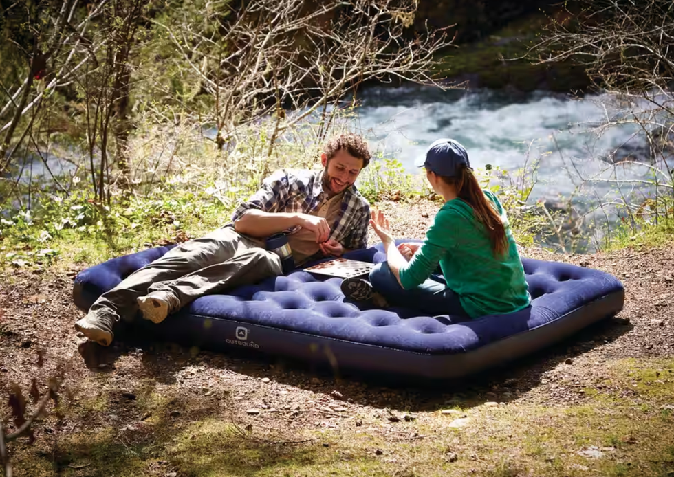 Deux personnes jouant aux dames sur un matelas gonflable au bord d'une rivi\u00e8re.