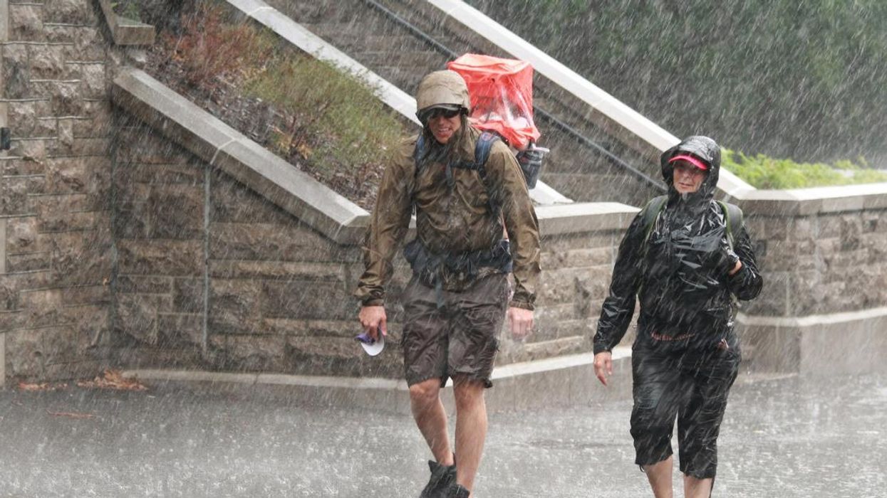 Deux personnes qui marchent sous la forte pluie.