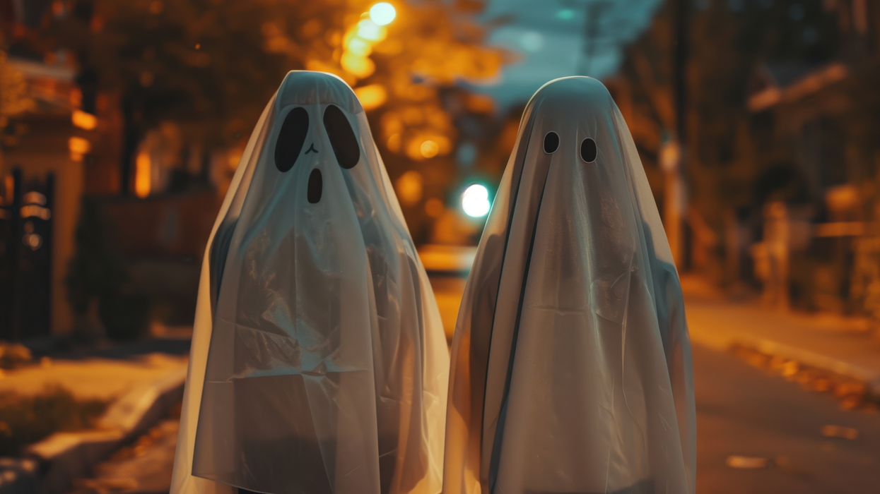 Deux personnes vêtues de costumes de fantôme dans une rue un soir d'automne.