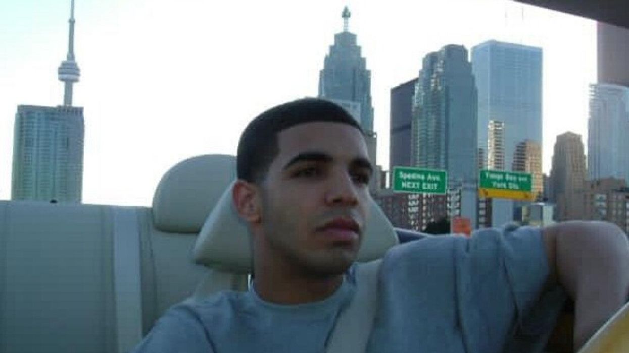 Drake driving a convertible with the CN Tower visible behind him.