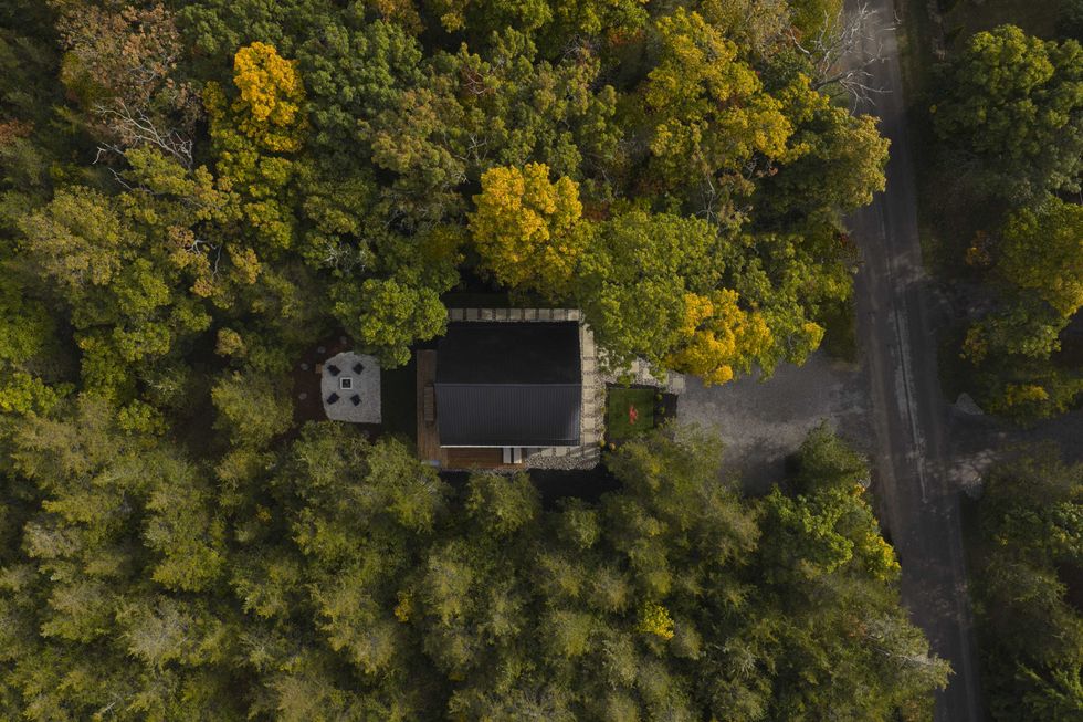 Drone view of a modern house nestled among trees in Prince Edward County, showcasing its secluded forest setting.