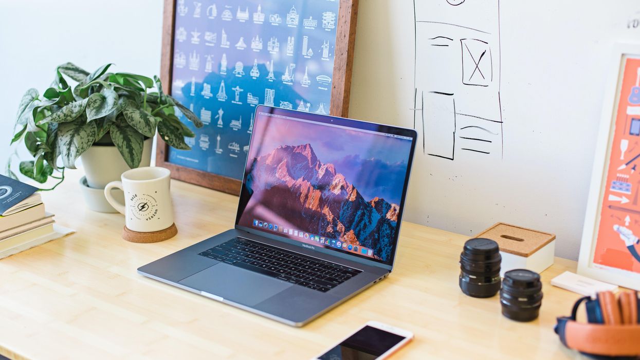 E laptop and a cellphone on a desk surrounded by other office supplies and decorations.