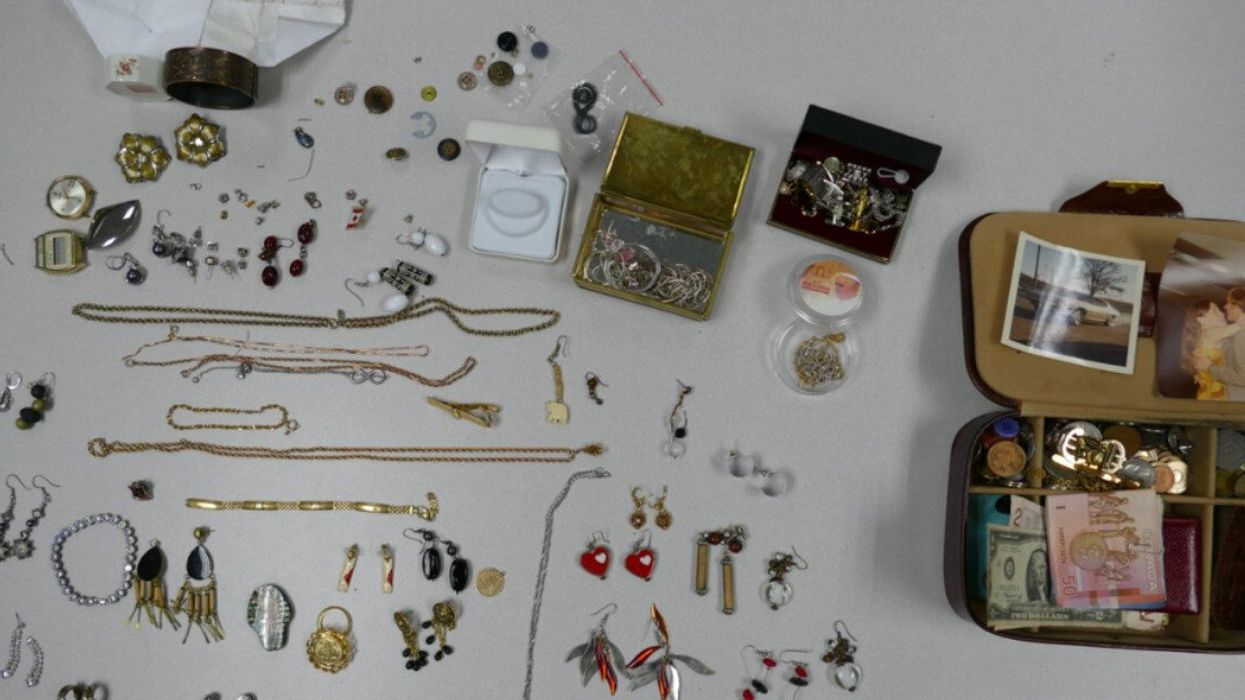 Earrings, necklaces, braclets, jewelry boxes, cash and photos laid out on a table.