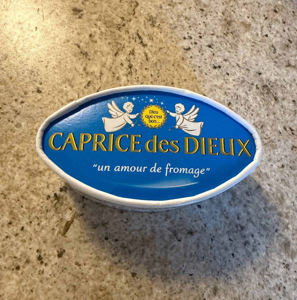 Emballage bleu du fromage Caprice des Dieux achet\u00e9 au Liquidation Marie pos\u00e9 sur un comptoir.