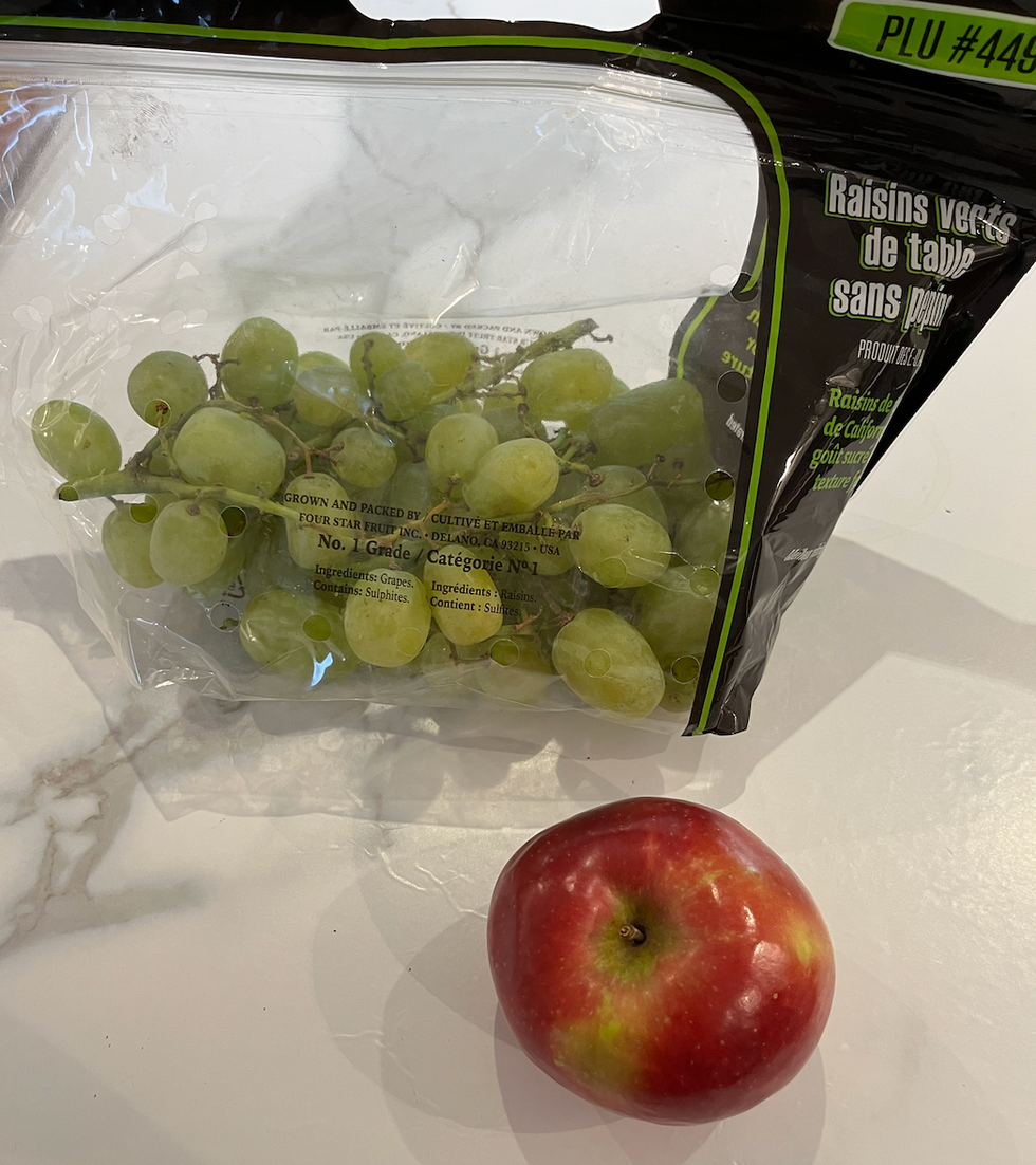 Emballage de \u200braisins vert et pomme rouge d\u00e9pos\u00e9s sur un comptoir.