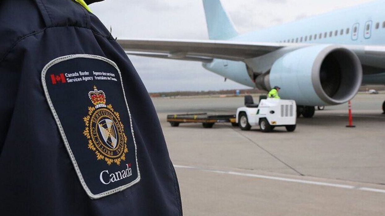 Employé de l'Agence des services frontaliers du Canada devant un avion.