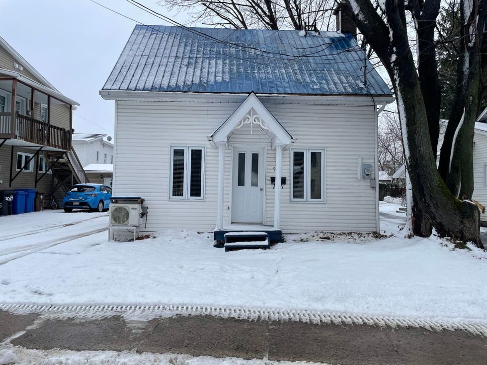 Fa\u00e7ade d'une maison \u00e0 \u00e9tages blanche \u00e0 vendre au Qu\u00e9bec.