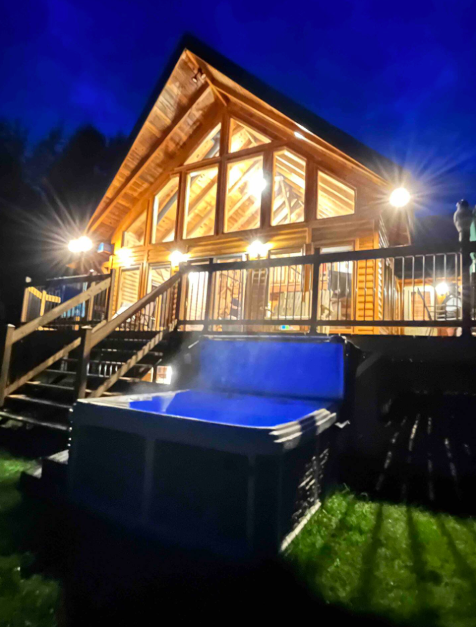 Face arri\u00e8re d'un chalet avec un spa illumin\u00e9.