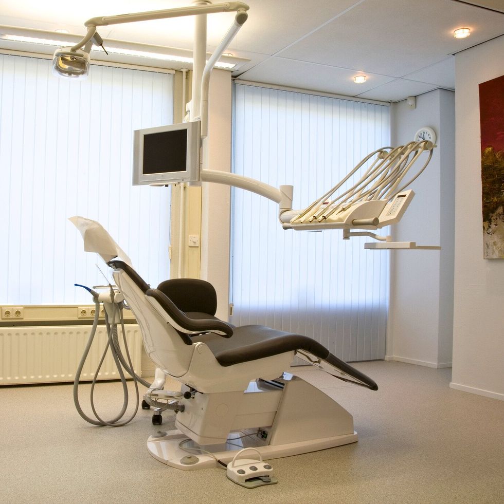 Fauteuil inclinable avec bras articul\u00e9s et ensemble d'instruments dentaires.