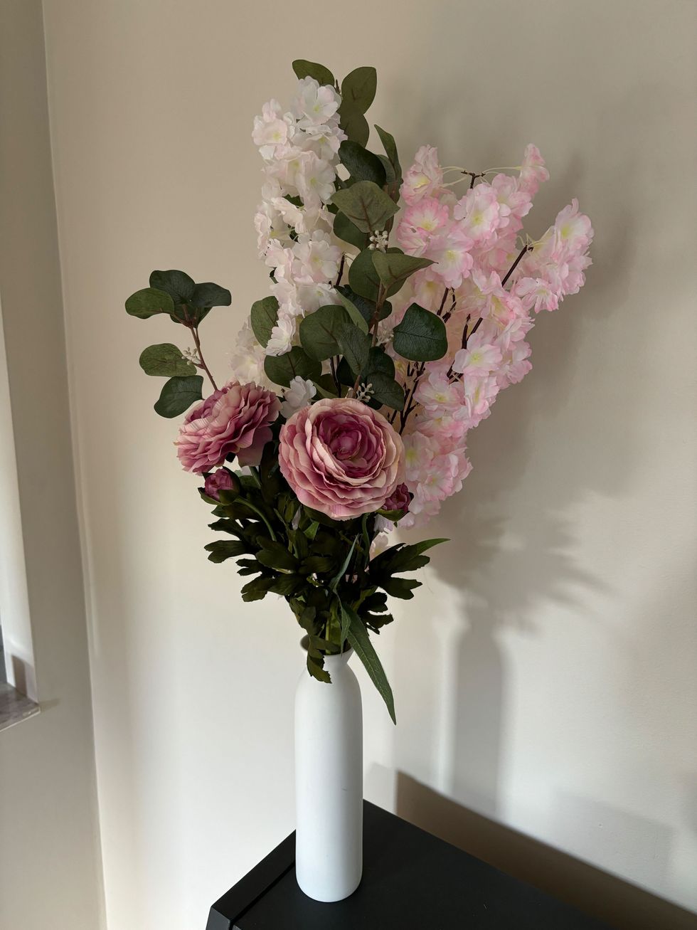 Faux flowers in a white vase.