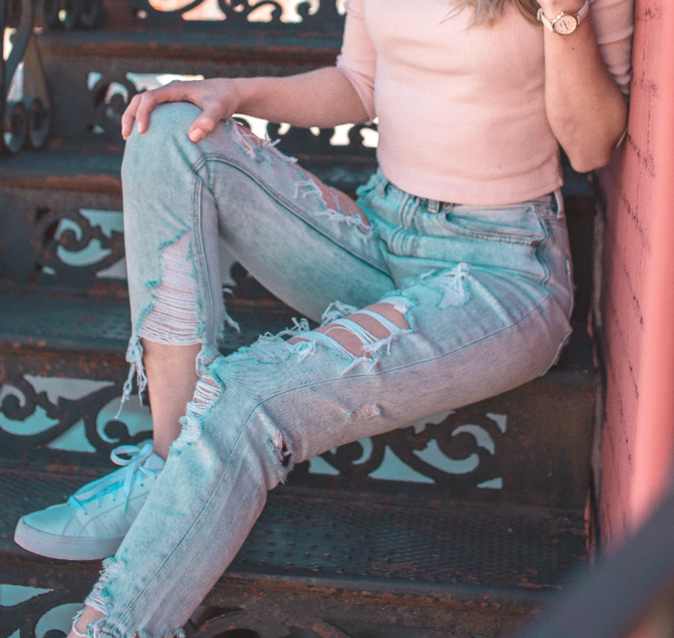 Femme, portant des jeans trou\u00e9s, assises sur un escalier.
