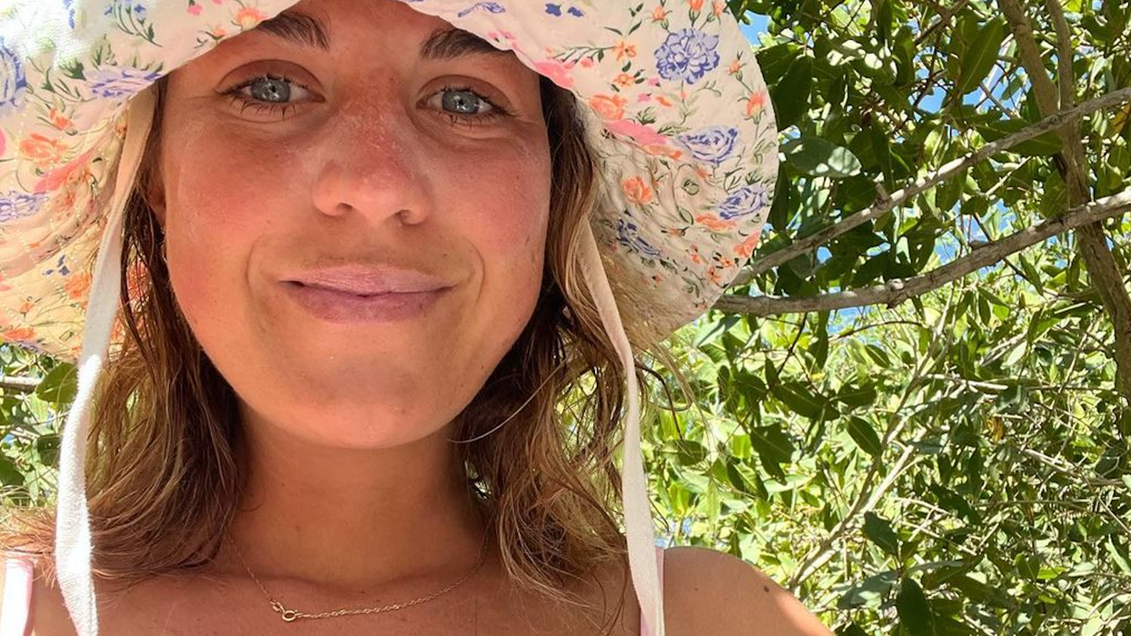 femme portant un chapeau posant devant un arbre
