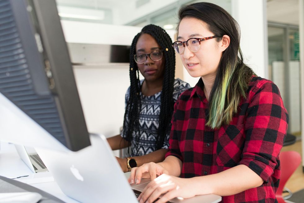 Femme portant un chemisier \u00e0 carreaux rouge et noir utilisant un MacBook.