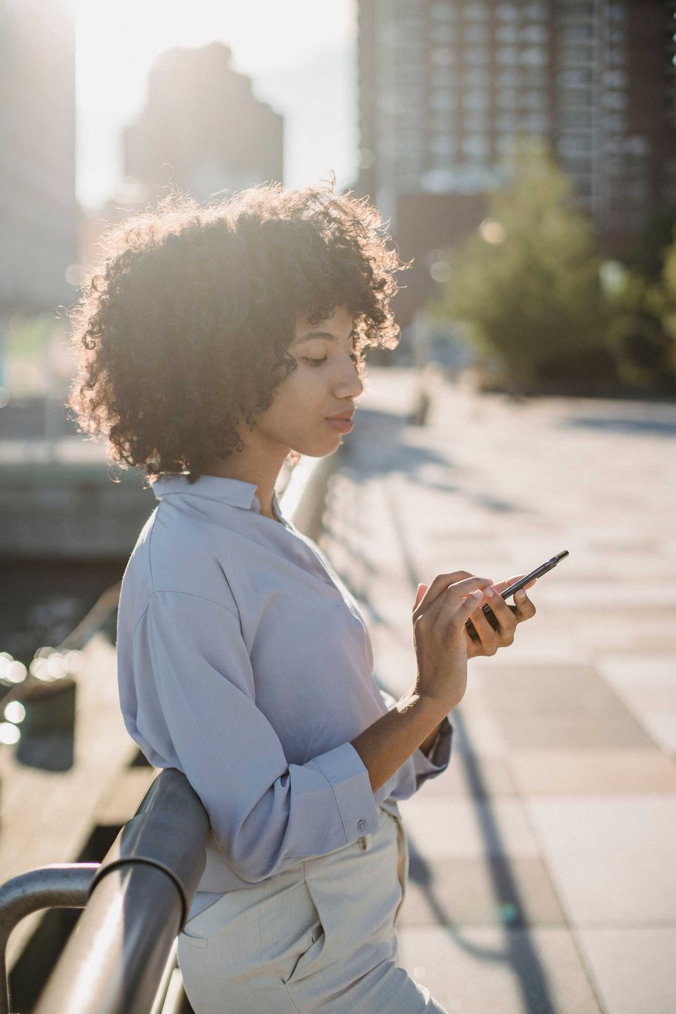 Femme utilisant son t\u00e9l\u00e9phone intelligent \u00e0 l'ext\u00e9rieur.