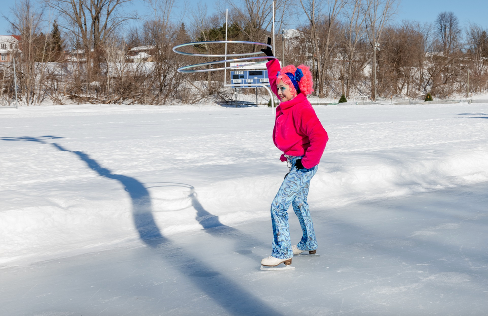 Femme v\u00eatue de rose bonbon et d'une perruque rose bonbon qui patine avec des anneaux m\u00e9talliques \u00e0 la main.
