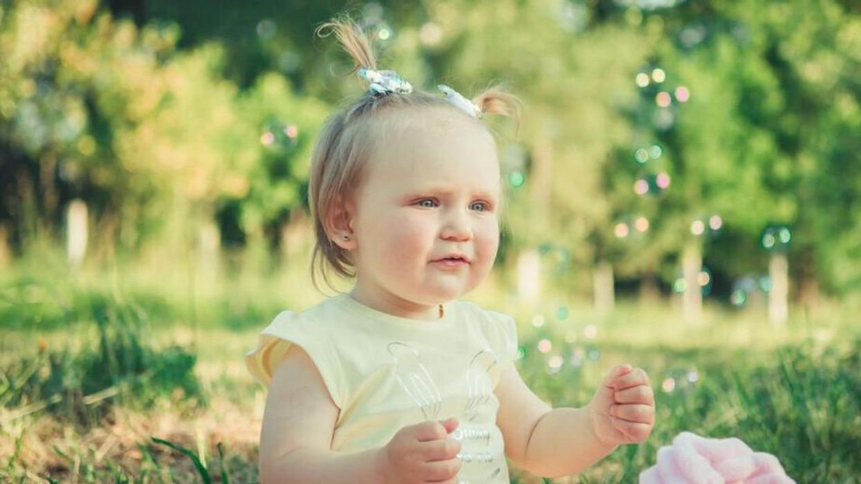 Fillette assise dans l'herbe.