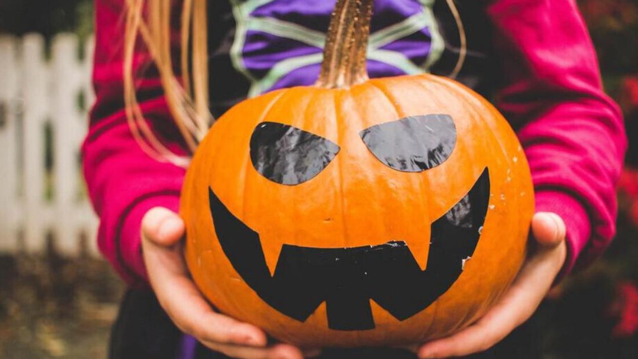 Fillette tenant une citrouille d'Halloween.