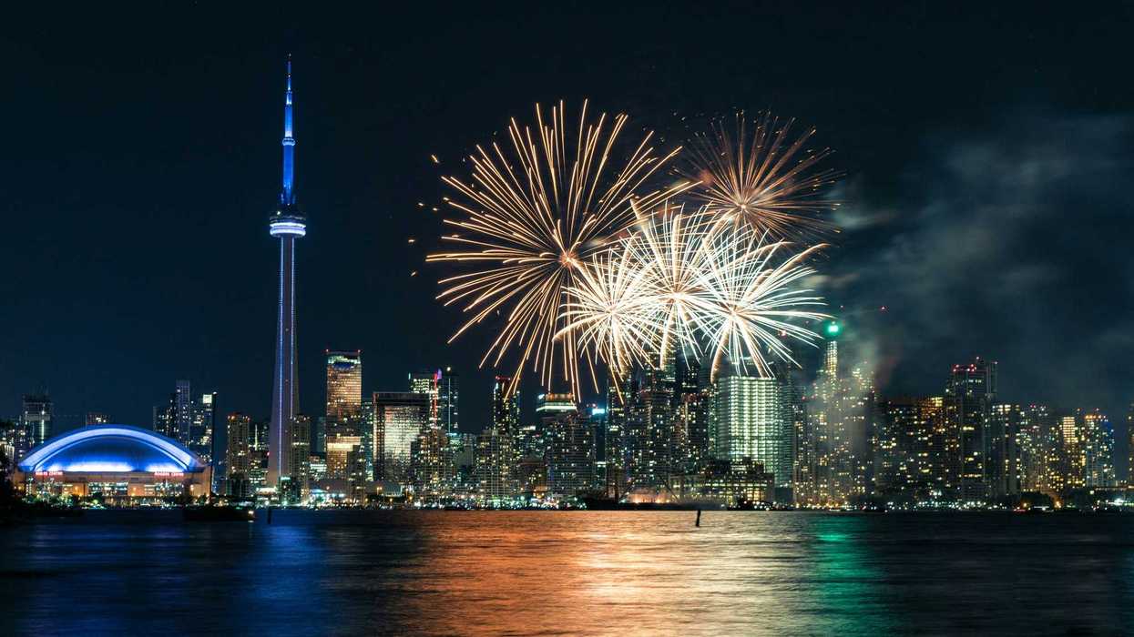 fireworks in the sky alongside toronto skyline and lake ontario