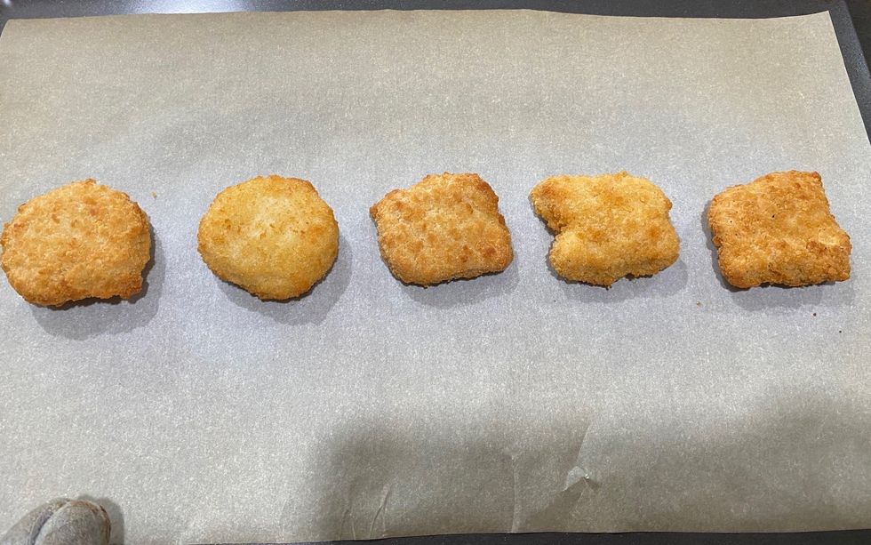 Five chicken nuggets on a baking sheet.