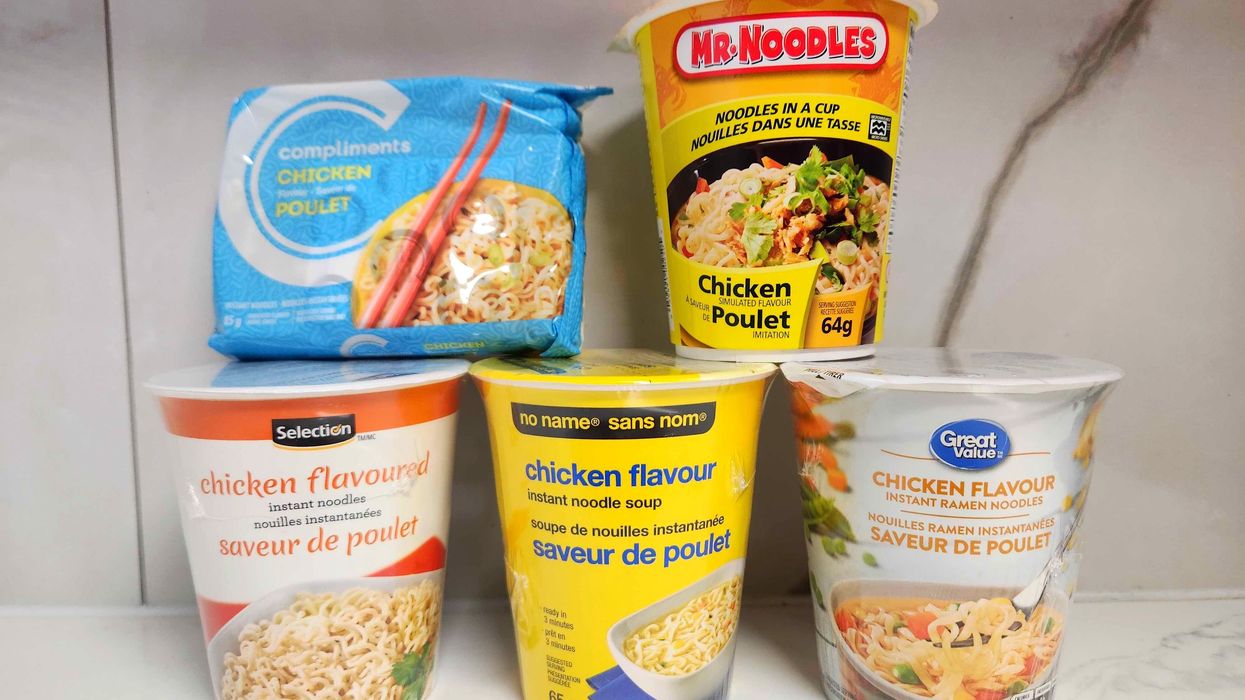 Five packages of instant noodles against a white marble background.