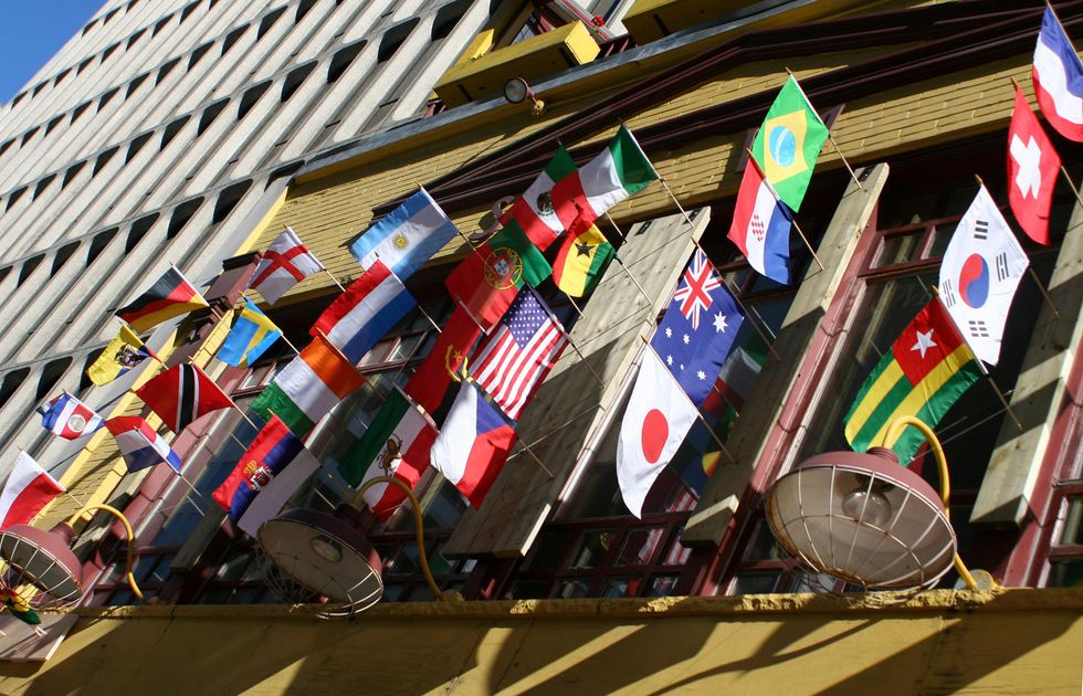 Flags from around the world hanging in front of a building.