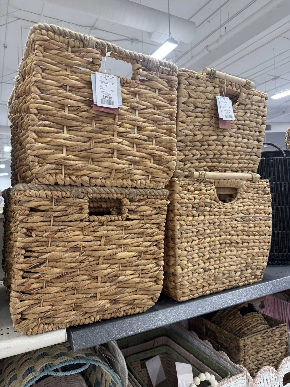Four brown wicker baskets sitting on a store shelf.