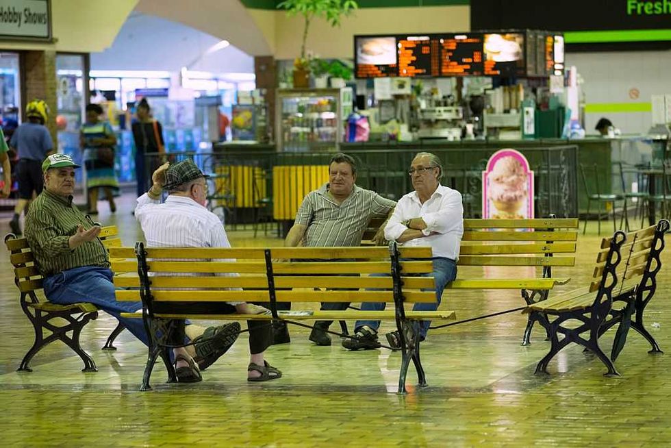 four people sitting on benches in the galleria mall in toronto