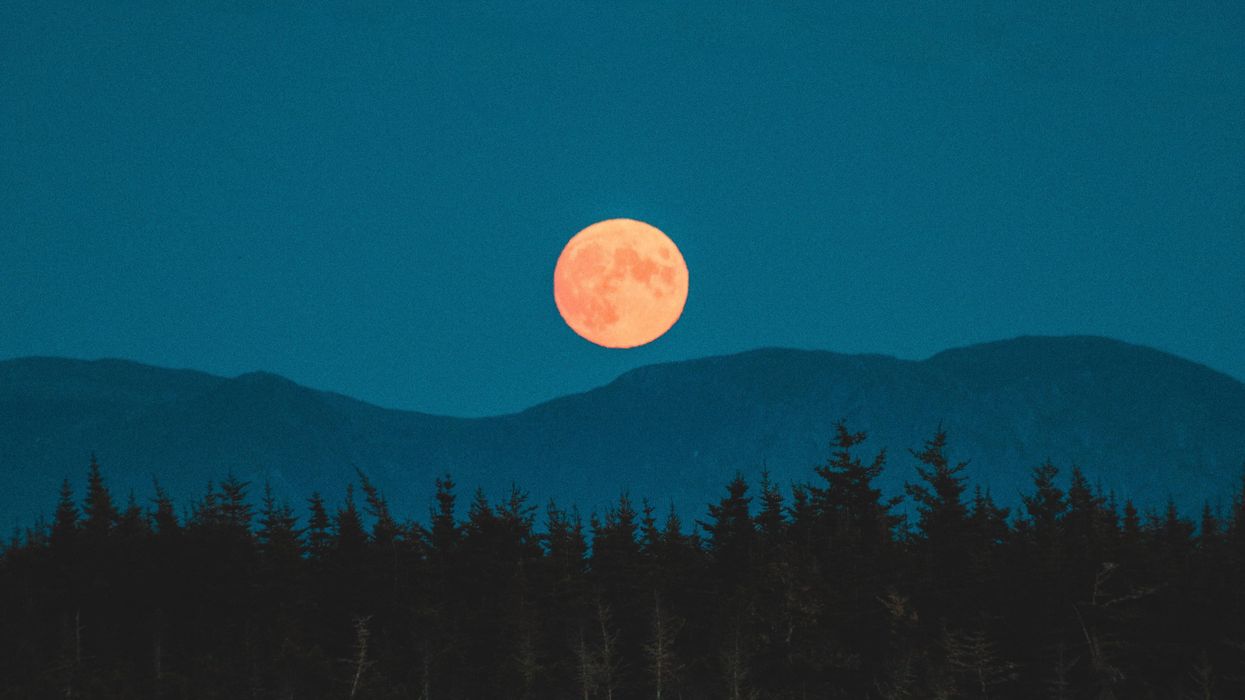 Full moon rising over mountains.