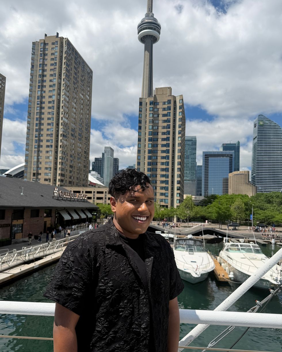 Geerthan stands in front of the marina at Harbourfront with the Toronto skyline and CN tower behind.