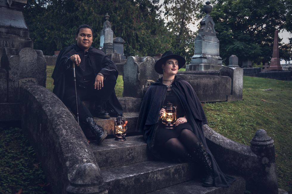 Ghost tour guides with lanterns in a cemetery.