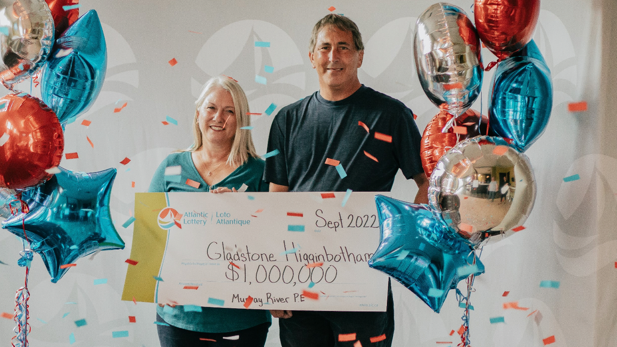 Gladstone Higginbotham and his wife holding a Lotto 6/49 cheque.
