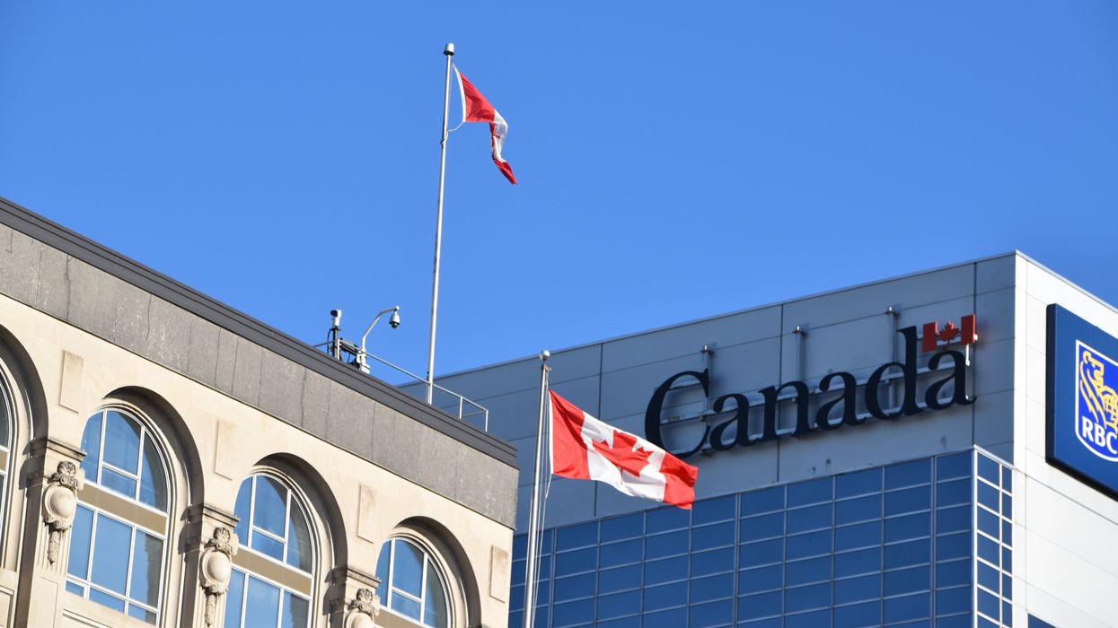 government of canada sign on a building and two canadian flags