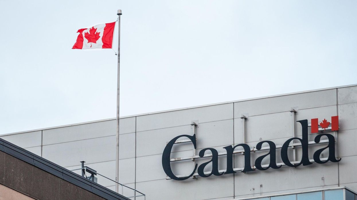 Government of Canada sign on an office building with a Canadian flag in front of it.