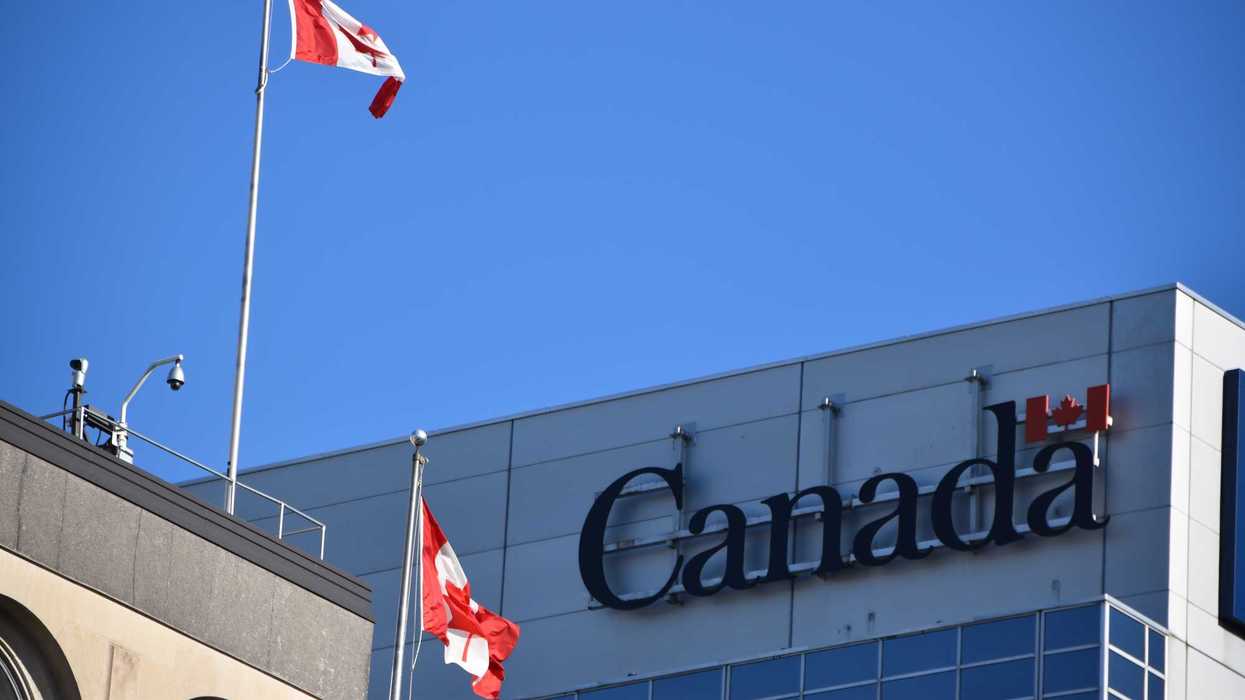 government of canada sign on building next to canadian flags