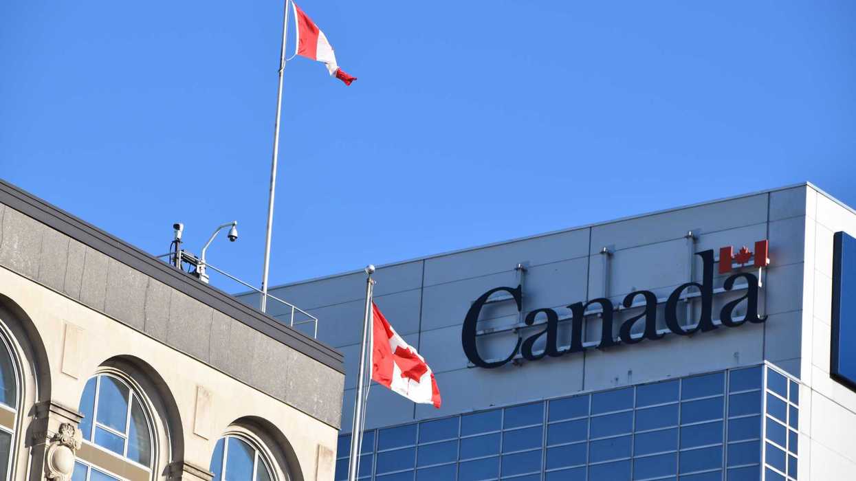 government of canada sign with canadian flags on building in ottawa
