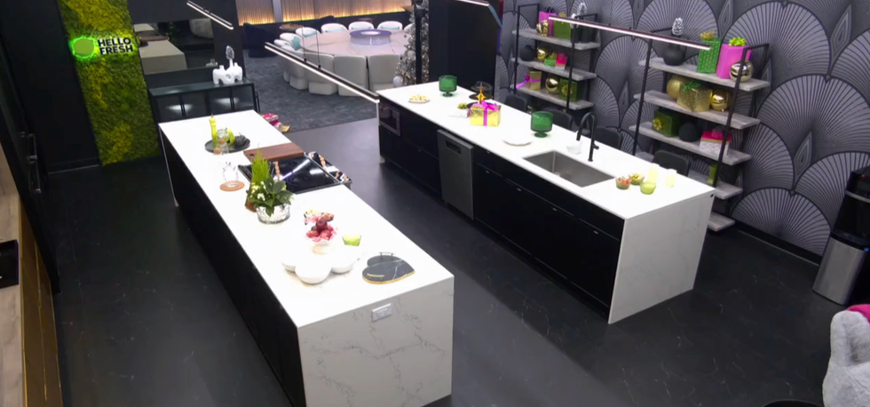 Grande cuisine avec \u00eelot blanche, mur et plancher noirs.