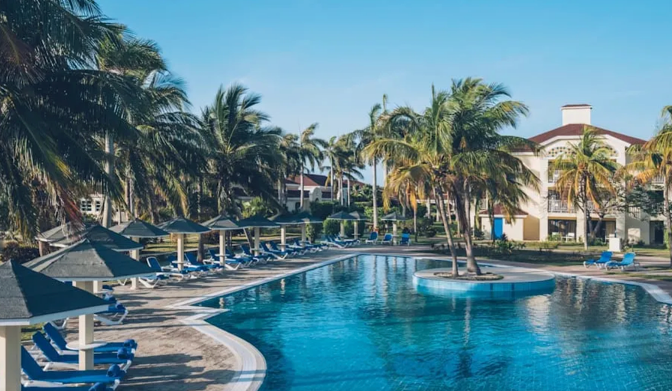 Grande piscine avec palmiers et chaises longues.