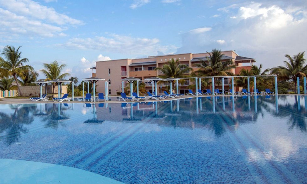 Grande piscine d'un h\u00f4tel entour\u00e9e de palmiers.