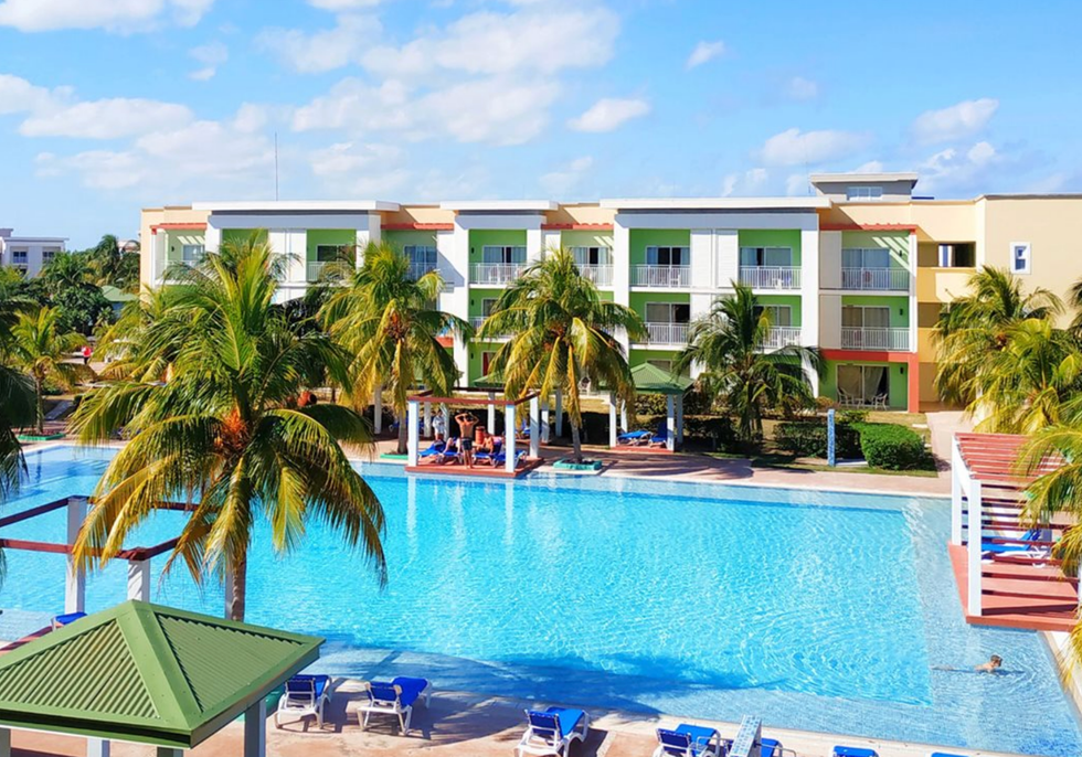 Grande piscine d'un h\u00f4tel entour\u00e9e de palmiers.