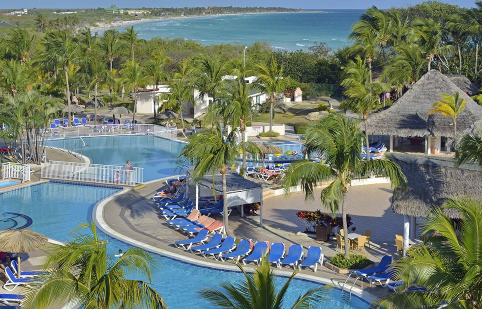 Grande piscine d'un h\u00f4tel entour\u00e9e de palmiers.