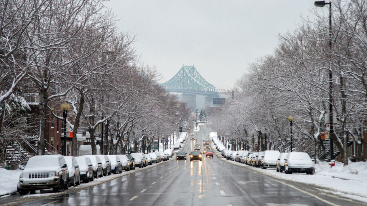 Grande rue avec des véhicules enneigés à Montréal.