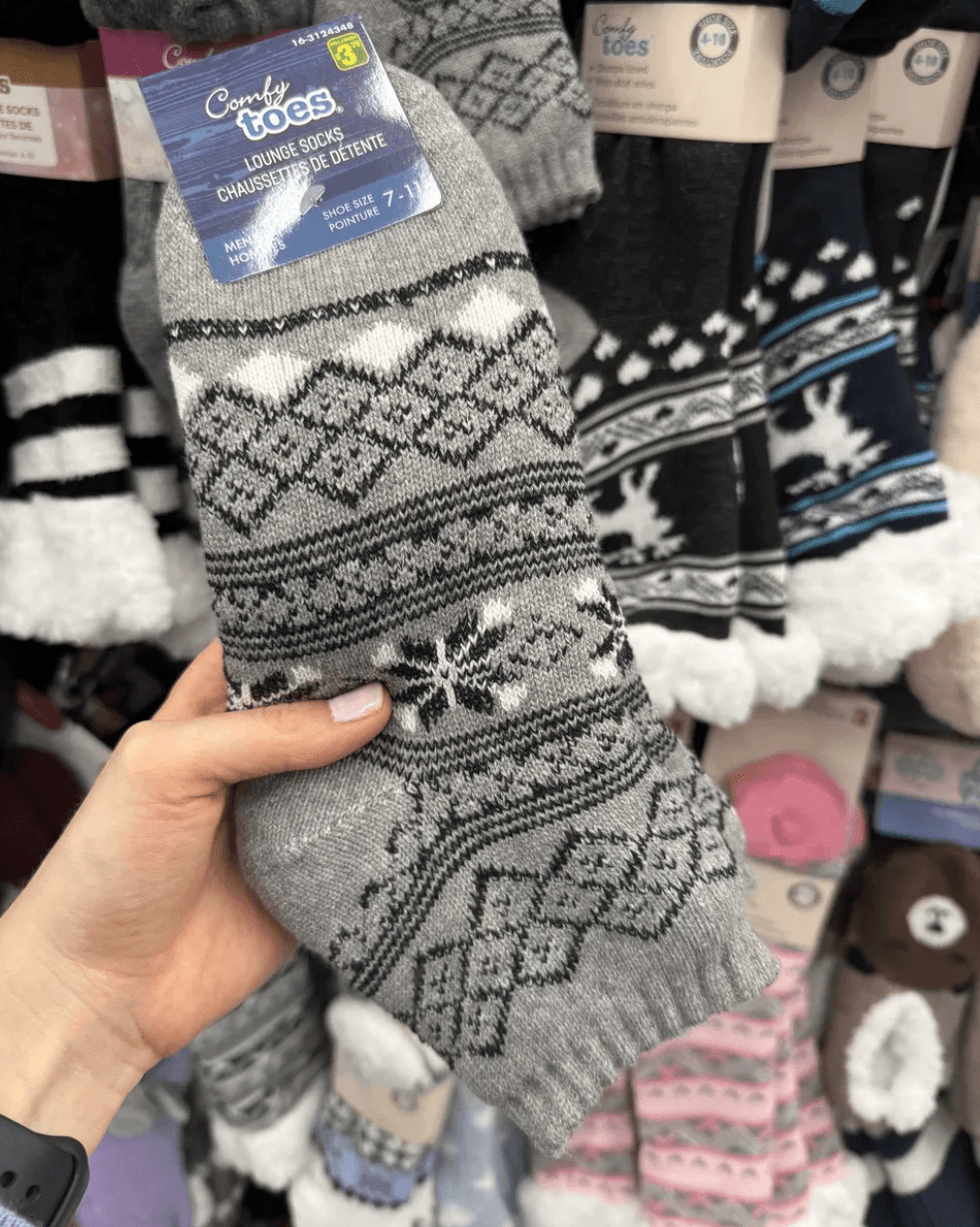 Gray patterned socks held in hand, displayed among other colorful socks.
