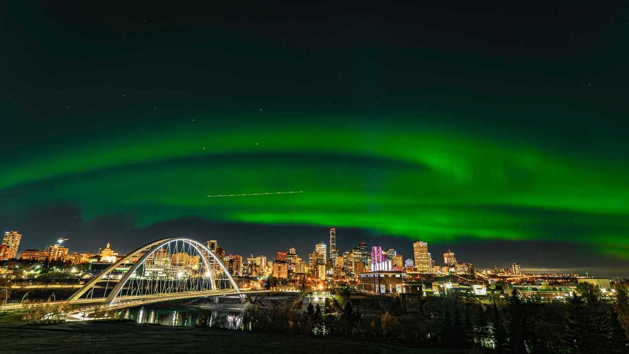 green northern lights in night sky over city buildings in edmonton alberta