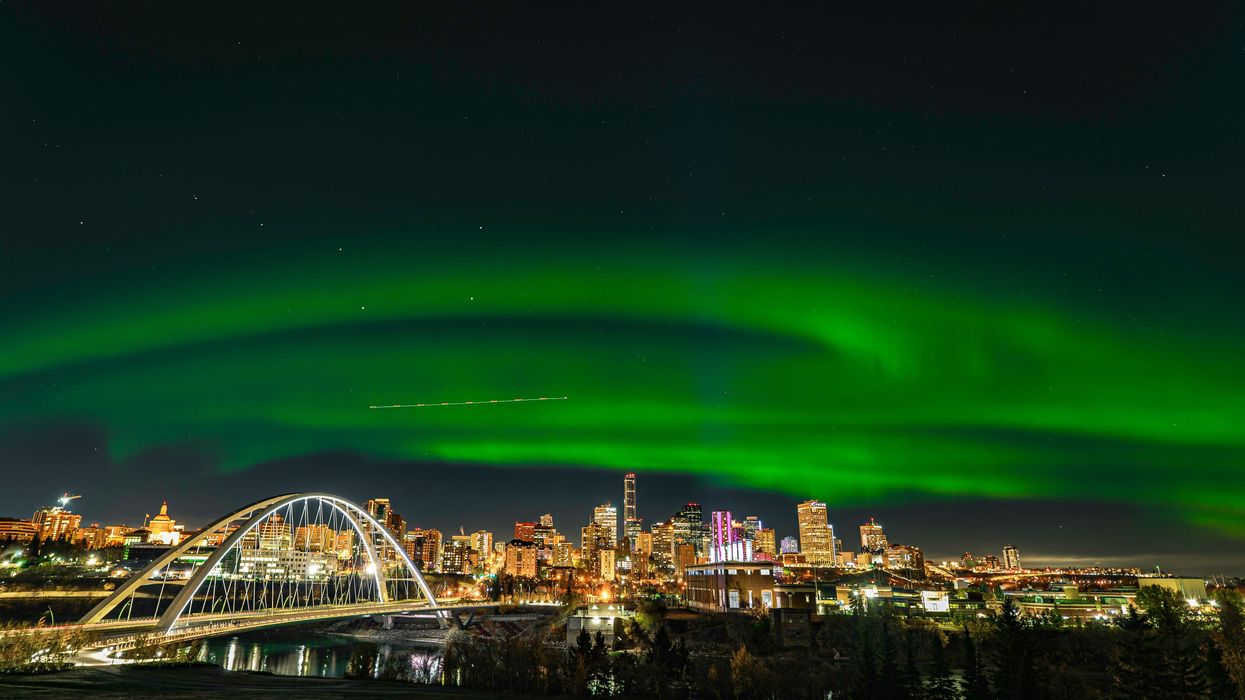 green northern lights in the sky above city buildings in edmonton, alberta