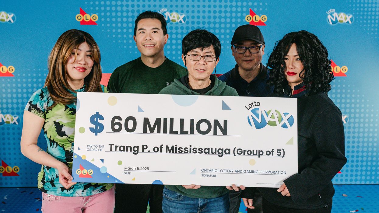 group of lotto max winners holding a $60 million cheque