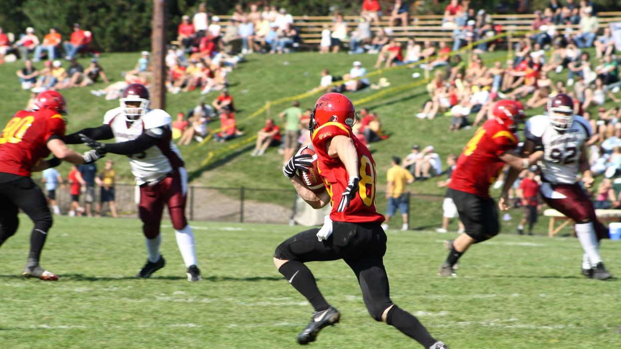 Guelph player running with football during a game against McMaster.