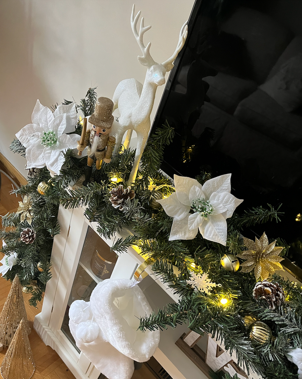 Guirlande de No\u00ebl orn\u00e9e de fleurs blanches et de d\u00e9corations dor\u00e9es vue de pr\u00e8s.