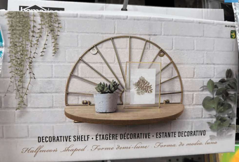 Half-moon shelf with plants and artwork on a white brick wall background.